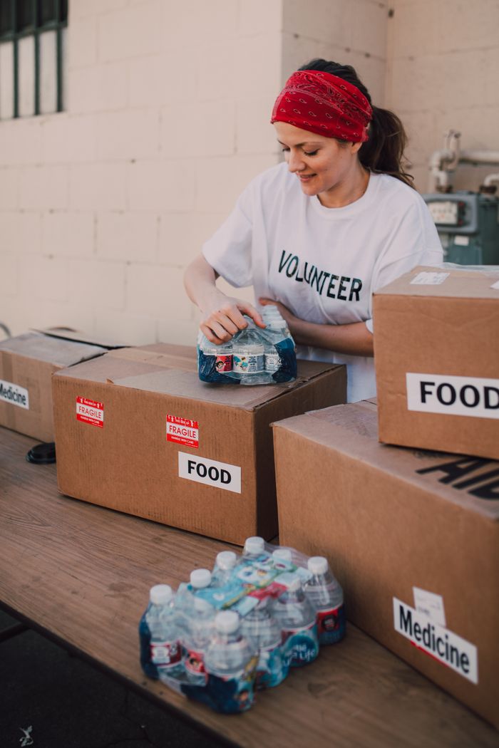 A volunteer packs food and water for a charity event held outdoors, highlighting community support.